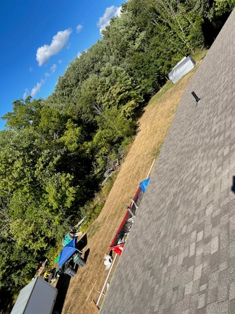 Gray shingle roof overlooking a wooded yard with equipment below
