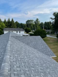 Completed gray shingle roof overlooking a lawn and neighboring homes