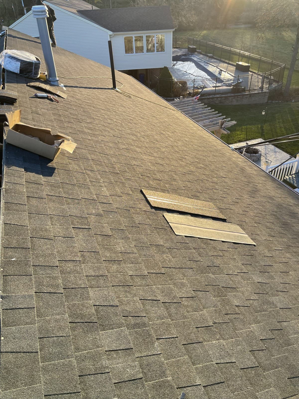 Shingle roof with a vent, tools, and loose materials during installation