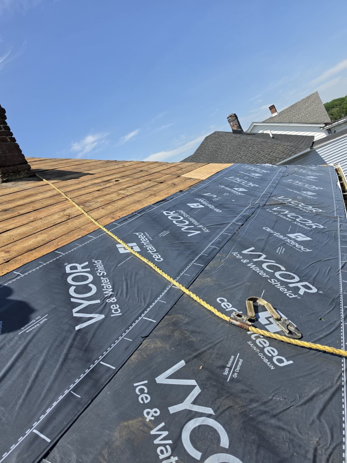 Dark roofing membrane beside exposed wood decking and a brick chimney