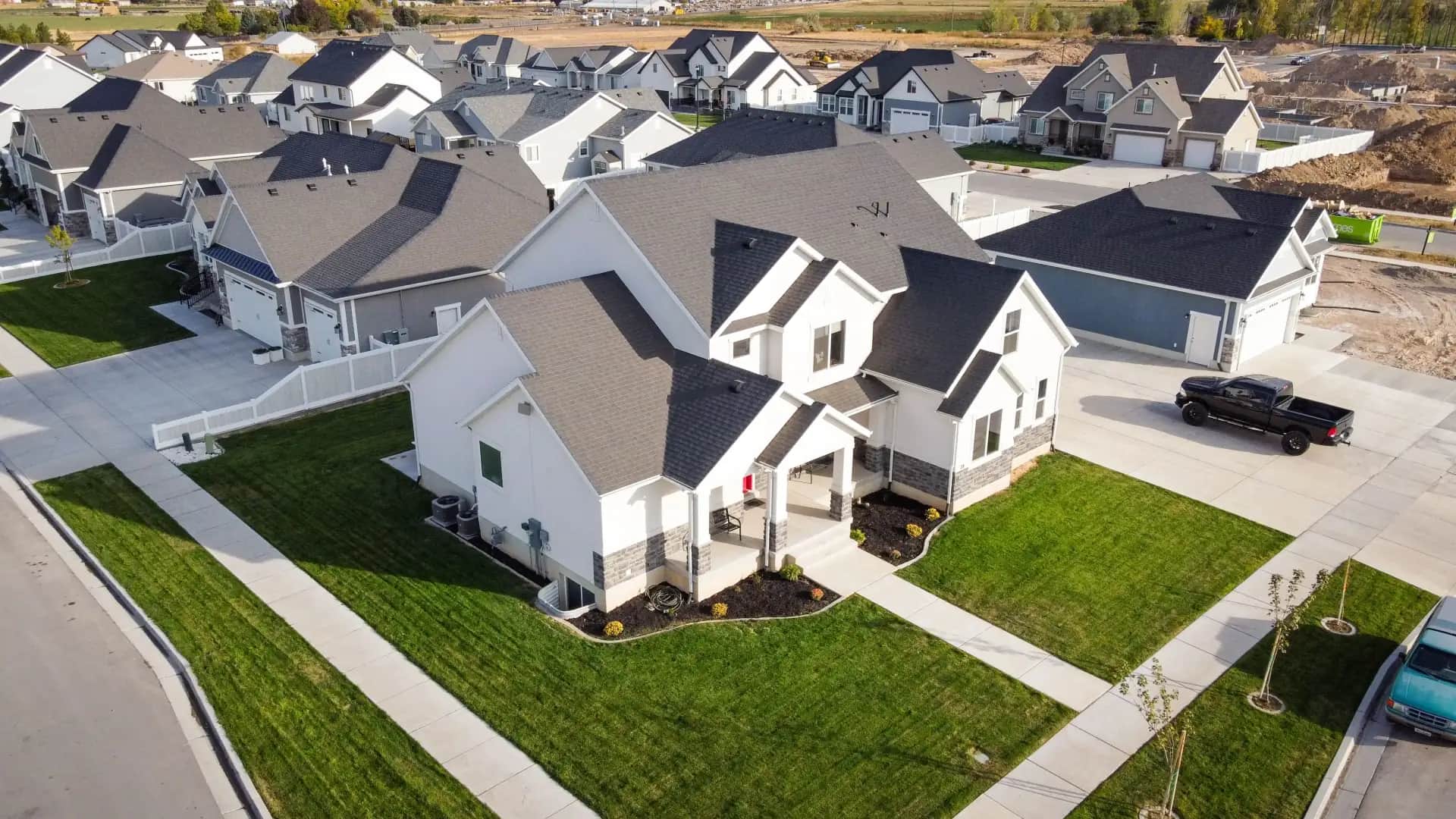 Detached homes with gray roofs, front lawns, and driveways