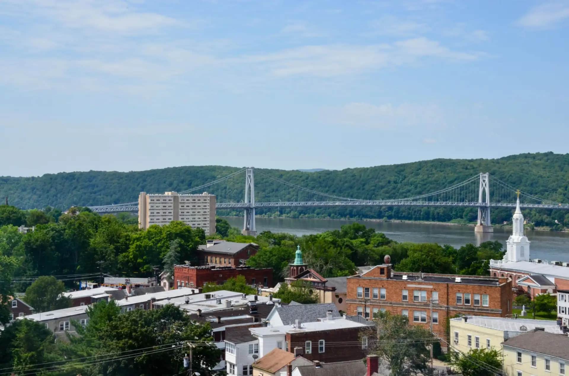 Bridge spanning the Hudson River behind buildings and a church steeple