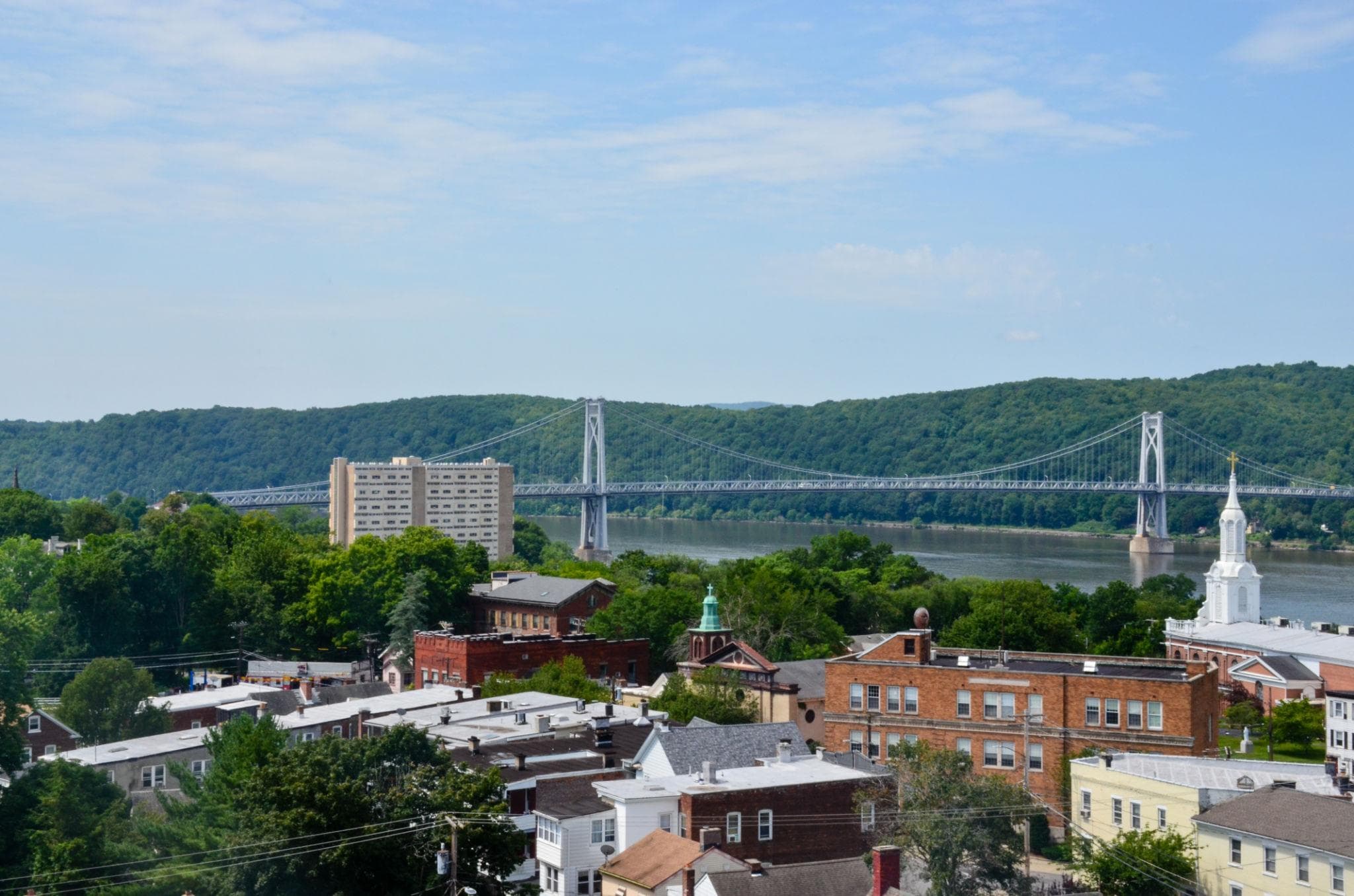 Bridge spanning the Hudson River behind buildings and a church steeple