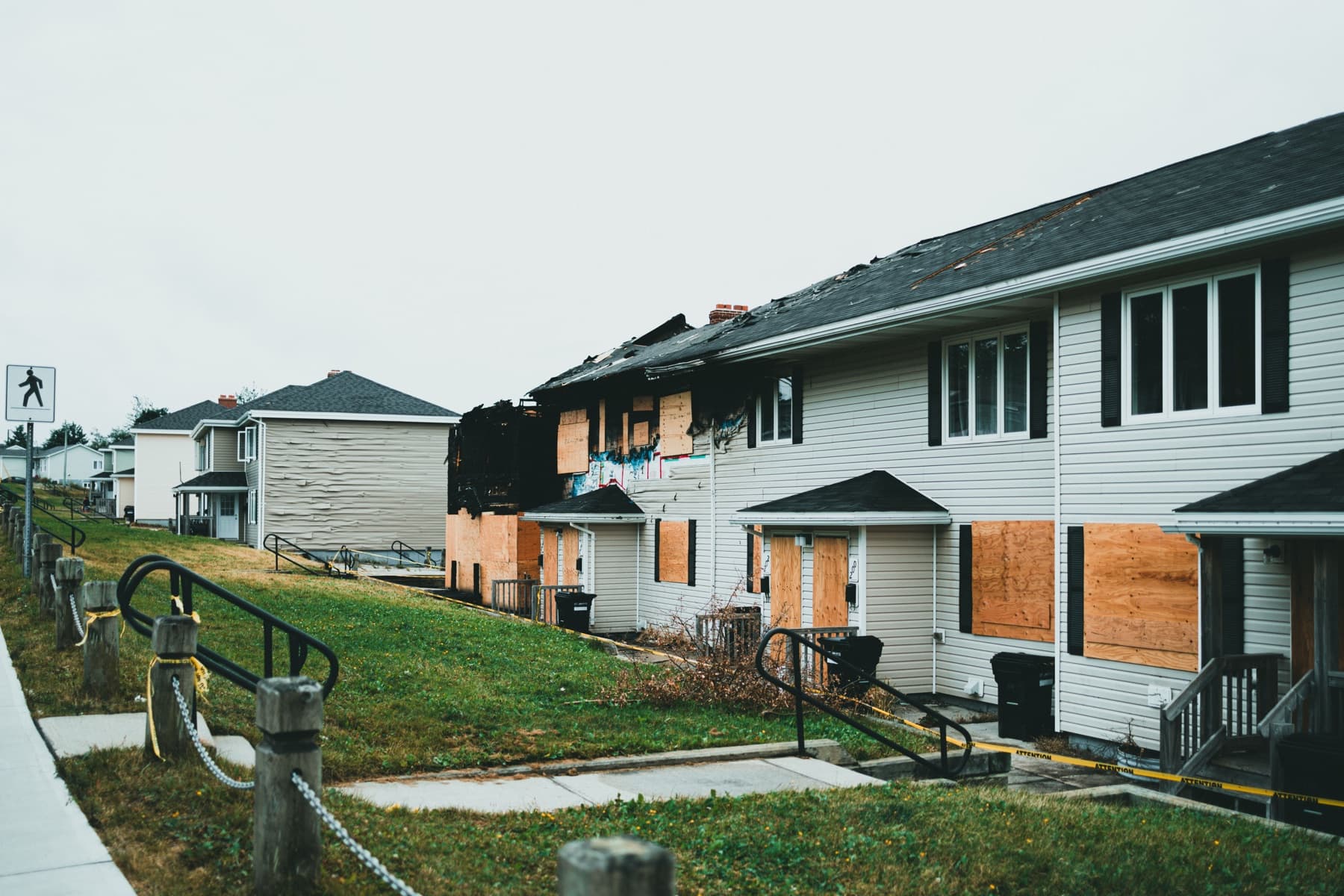 Residential building with damaged roofing and boarded windows